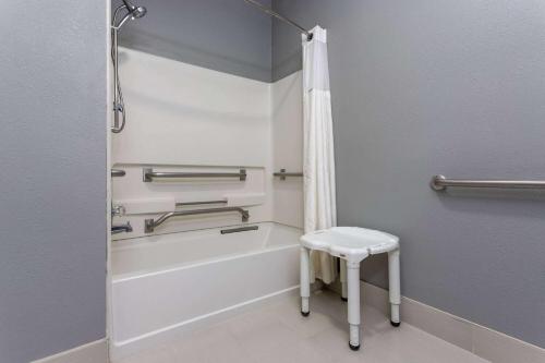 a bathroom with a bath tub and a stool in it at Ramada by Wyndham Sellersburg/Louisville North in Sellersburg