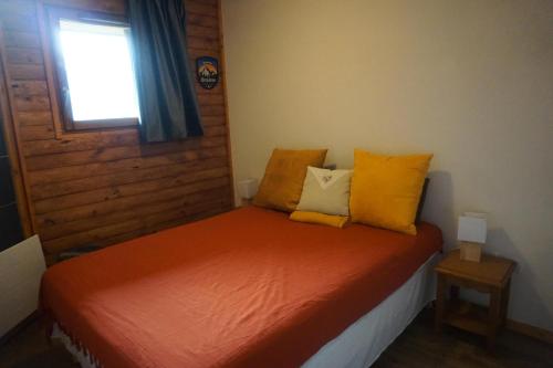- une chambre avec un lit doté de draps orange et d'oreillers jaunes dans l'établissement Résidence Cristallines - 2 Pièces pour 4 Personnes 59, à Orcières