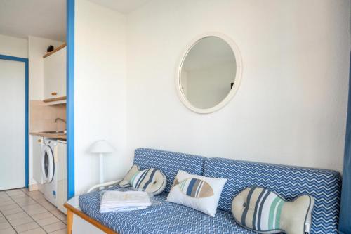 - un canapé bleu avec des oreillers et un miroir mural dans l'établissement Résidence Port Bourgenay - maeva Home - Appartement 2 pièces 4 personnes - Confort MAE-1720, à Talmont-Saint-Hilaire
