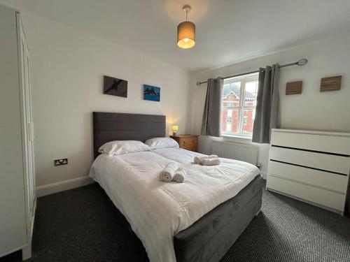 a bedroom with a bed with two towels on it at Spacious 2 Bed 2 Shower Apartment in Crewe