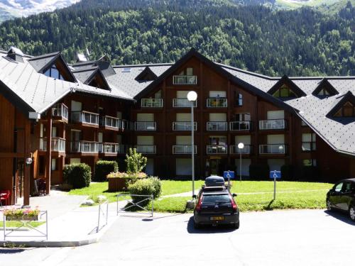 un grand bâtiment avec des voitures garées dans un parking dans l'établissement Résidence Combettes - Combettes E236 MAE-4834, aux Contamines-Montjoie