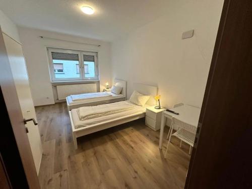 een slaapkamer met 2 bedden, een bureau en een raam bij ATRIUM - großzügige Wohnung BLÜCHER 2 in Ludwigshafen am Rhein