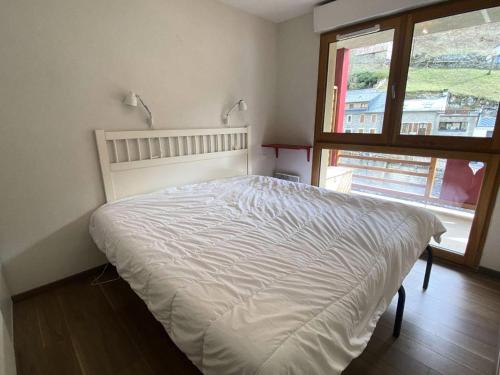 - un lit blanc dans une chambre avec fenêtre dans l'établissement Résidence Bois De Marie - Joli appartement avec balcons, parking et WIFI proche du centre de Barèges MAE-8644, à Barèges
