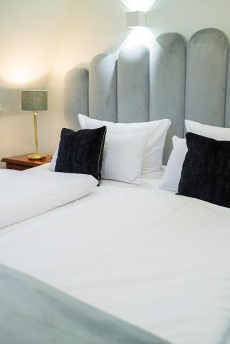 two white beds with black pillows in a room at Bernstein Schlosshotel Ballenstedt in Ballenstedt