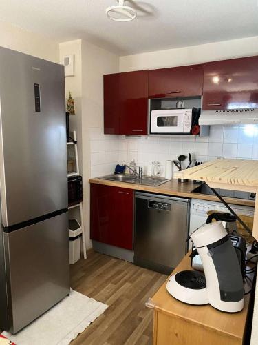 La cuisine est équipée de placards rouges et d'un réfrigérateur en acier inoxydable. dans l'établissement Résidence Bois De Marie - Appartement avec garage et WIFI, proche du centre de Barèges MAE-8724, à Barèges
