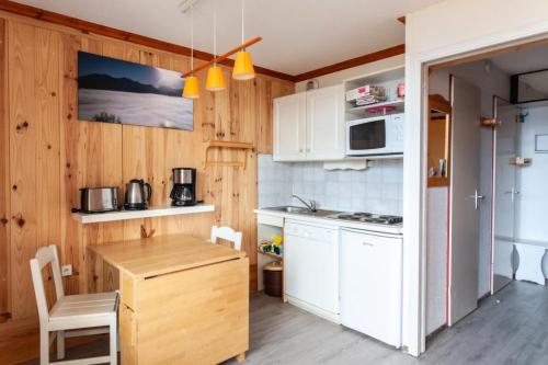 une cuisine avec des armoires blanches et une table en bois dans l'établissement Résidence Les Horizons d'Huez - maeva Home - Appartement 2 Pièces 5 Personnes - Sélection MAE-2698, à Huez