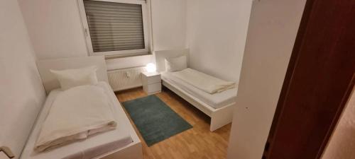 Cette petite chambre comprend 2 lits et une fenêtre. dans l'établissement ATRIUM - gemütliche Wohnung FRITZ HABER, à Ludwigshafen