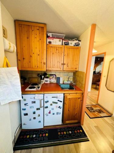 Elle comprend une petite cuisine avec des placards en bois et un évier. dans l'établissement Résidence Lienz - Joli T2 en duplex exposé sud MAE-8054, à Barèges