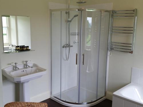 uma casa de banho com uma cabina de duche em vidro e um lavatório. em Upper Letton Farm em Leintwardine
