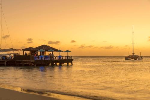 een dok met een boot op het water bij zonsondergang bij Hyatt Regency Aruba Resort & Casino in Palm-Eagle Beach