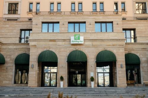 a building with a sign on the front of it at Holiday Inn Aktau, an IHG Hotel in Aktau