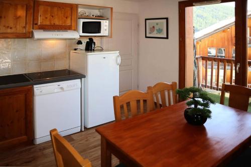 eine Küche und ein Esszimmer mit einem Tisch und einem Kühlschrank in der Unterkunft LES CHALETS DE BOIS MEAN - 2 Pièces pour 6 Personnes 024 in Les Orres