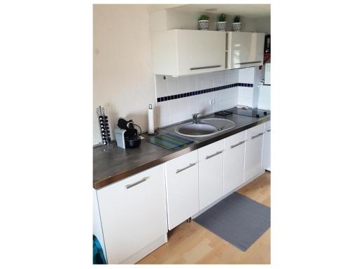une cuisine avec des armoires blanches et un évier dans l'établissement Résidence Port du Crouesty - maeva Home - Appartement 2 pièces 4 personnes - Confort MAE-3324, à Arzon