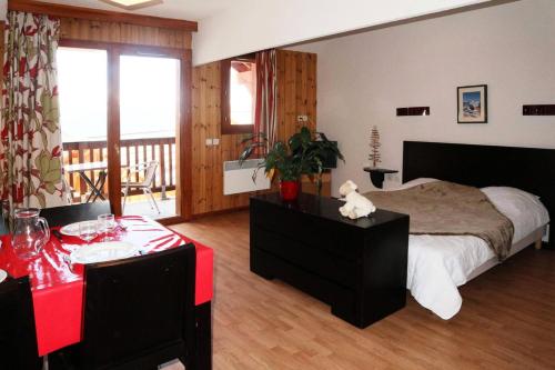 ein Schlafzimmer mit einem großen Bett und einem roten Tisch in der Unterkunft RESIDENCE LA COMBE D OR - Studio pour 4 Personnes 814 in Les Orres
