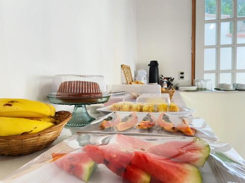 a table with several trays of fruit on it at Pousada Hospedagem Caribe in Arraial do Cabo