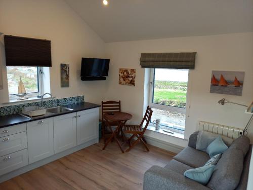 uma cozinha e sala de estar com um sofá e uma mesa em 380 The Bothy Cleggan em Leagaun