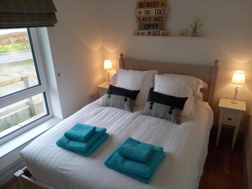 um quarto com uma cama branca e 2 almofadas azuis em 380 The Bothy Cleggan em Leagaun