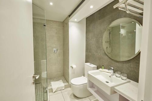 bagno con servizi igienici, lavandino e specchio di Garden Court Mthatha a Mthatha