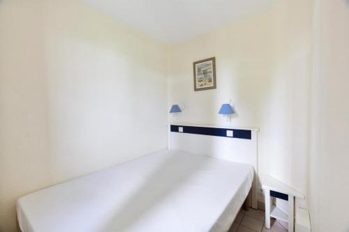 - un lit blanc dans une chambre blanche avec deux lampes dans l'établissement Résidence Port Bourgenay - maeva Home - Appartement 2 pièces 5 personnes Selection MAE-3681, à Talmont-Saint-Hilaire