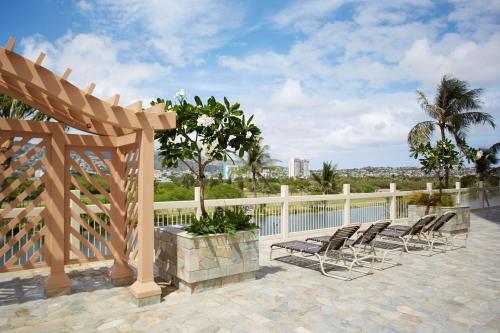 a patio with chairs and a wooden pergola at Skyline Island Colony Hotel in Honolulu
