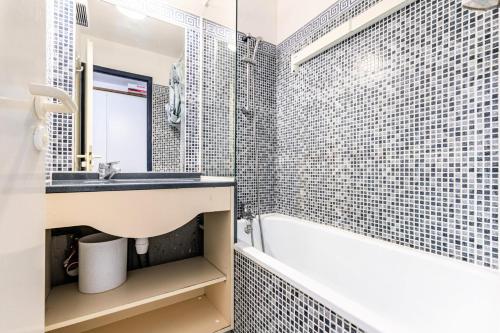 uma casa de banho com um lavatório, uma banheira e um espelho. em Résidence Port Bourgenay - maeva Home - Appartement 2 pièces 5 personnes - 39 em Talmont