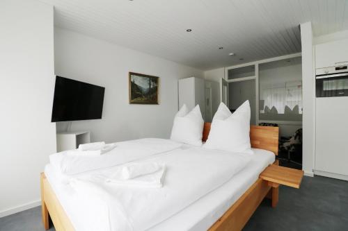a white bedroom with a large white bed with white pillows at Ferienwohnung "Hygge" in Schluchsee in Schluchsee