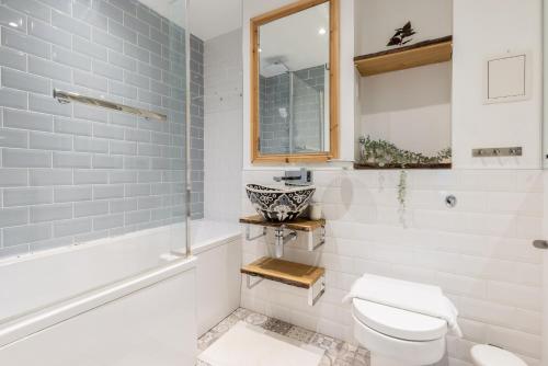 a bathroom with a toilet and a tub and a sink at The East Dulwich Collection in London