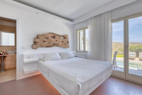 a white bedroom with a bed and a window at Mykonos Dream Villas in Elia