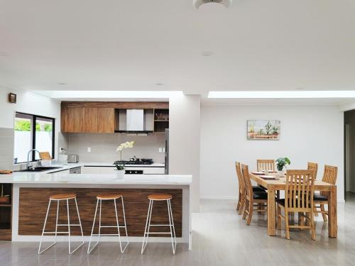 a kitchen and dining room with a table and chairs at Luxury Bay Vacation Home 5 Ensuites & Pool in Whangaparaoa