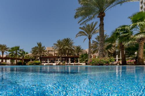 a large swimming pool with palm trees in the background at The Diplomat Radisson Blu Residence in Manama