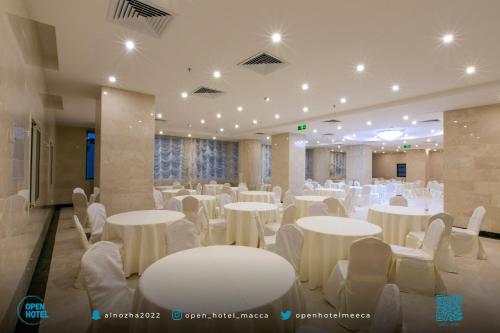 un salón de banquetes con mesas blancas y sillas blancas en فندق اوبن هوتيل مكه المكرمه en La Meca