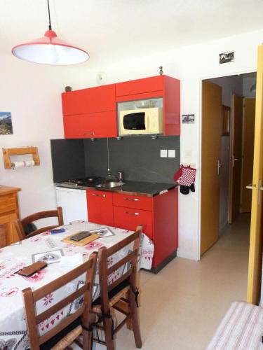 une cuisine avec des placards rouges et une table avec des chaises dans l'établissement Residence Le Thymel - 2 pièces cabine 4 personnes exposé Est MAE-8644, à Valloire