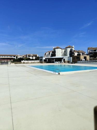 une piscine vide avec des bâtiments en arrière-plan dans l'établissement Résidence Palmyra - Appartement 2 pièces 4 couchages LE BARCARES MAE-5754, au Barcarès