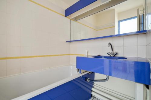 La salle de bains est pourvue d'un lavabo bleu et d'une baignoire. dans l'établissement Résidence Port du Crouesty - maeva Home - Appartement 2 pièces 5 personnes - Confort - Vue mer MAE-9598, à Arzon