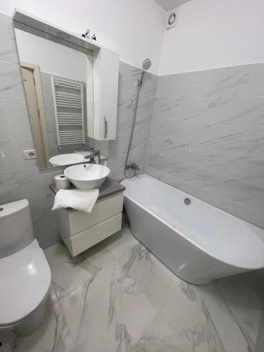 La salle de bains est pourvue d'un lavabo, d'une baignoire et de toilettes. dans l'établissement Luxury Apartment, à Piteşti