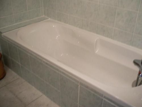 uma banheira branca na casa de banho com azulejos verdes em Chalet Les Aiguilles - Pièces 34 em Valloire