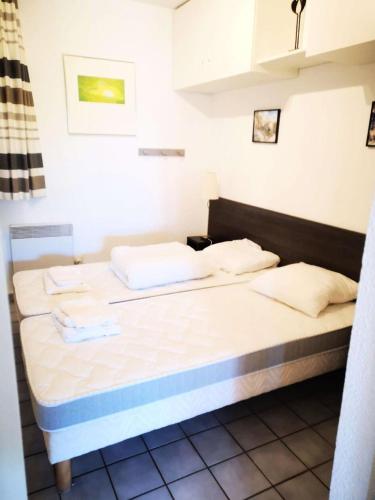 un lit dans une chambre avec deux oreillers dessus dans l'établissement Résidence Palmyra - Appartement 2 pièces avec wifi au rez-de-chaussée à LE BARCARES - CAP COUDALERE MAE-4404, au Barcarès