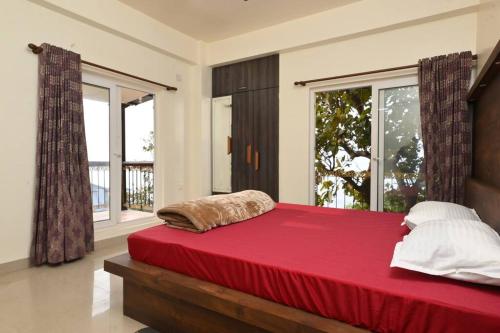 - une chambre avec un grand lit rouge et une grande fenêtre dans l'établissement Camilla Living- A Luxury Escape by the Riverside!, à Guwahati