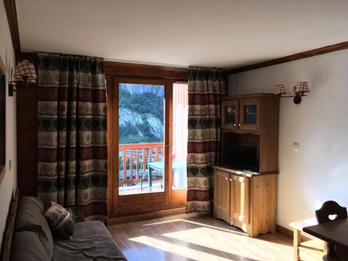 uma sala de estar com um sofá e uma porta de vidro deslizante em Résidence Gentiane Hameau De La Vallee D'or - 2 Pièces pour 4 Personnes 84 em Valloire