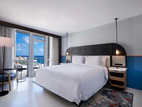 Hilton Garden Inn San Juan Condado في سان خوان: غرفة نوم بسرير ابيض كبير وبلكونة