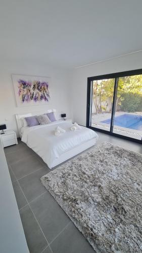 a white bedroom with a bed and a rug at Moraira B5 in Moraira