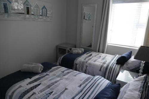 a bedroom with two beds and a mirror and a window at Beach Club Unit 207 in Mossel Bay