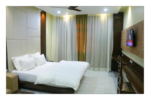 a bedroom with a white bed and a television at Hotel Grand Surya in Kodarma