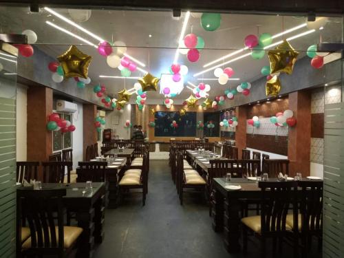 uma sala de jantar com mesas, cadeiras e balões em Hotel Grand Surya em Kodarma