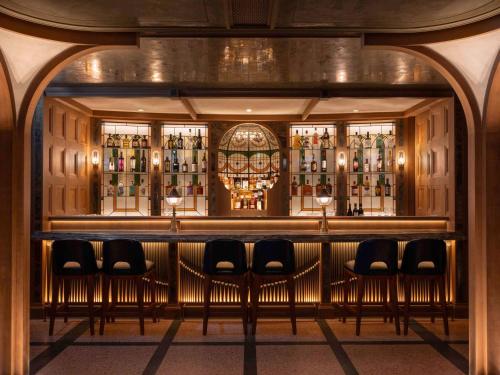 a bar with stools in front of a wall of wine bottles at Mondrian Hong Kong in Hong Kong