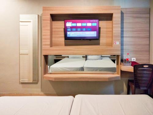 a room with a bed and a tv on a wall at Wikost Premiere Inn Mitra RedDoorz in Plelen
