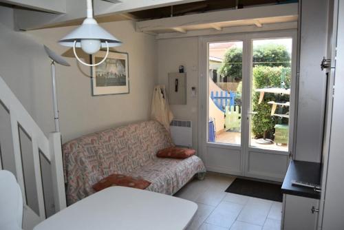 ein Wohnzimmer mit einem Sofa und einem Fenster in der Unterkunft Résidence LE HAMEAU DES PECHEURS - Maisons & Villas pour 4 Personnes 34 in Port Leucate