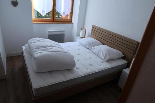 a bed with white sheets and pillows on it at Chalet Du Regain - 3 Pièces pour 8 Personnes 94 in Valloire