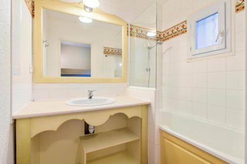 W łazience znajduje się umywalka, lustro i wanna. w obiekcie Les Issambres Corniche - maeva Home - Appartement 2 pièces 5 personnes Confort MAE-1353 w mieście Les Issambres