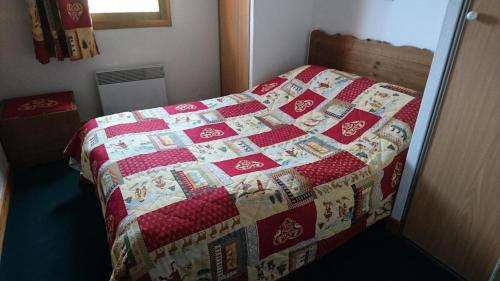 a bed with a quilt on it in a bedroom at Edelweiss Chalets De La Vallee D'or - 2 Pièces pour 4 Personnes 34 in Valloire